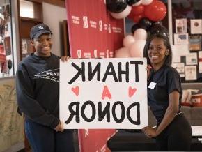 两名女学生举着一张海报，上面写着感谢捐赠者